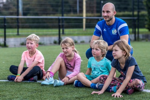 Kinderen luisteren aandachtig naar sportuitleg